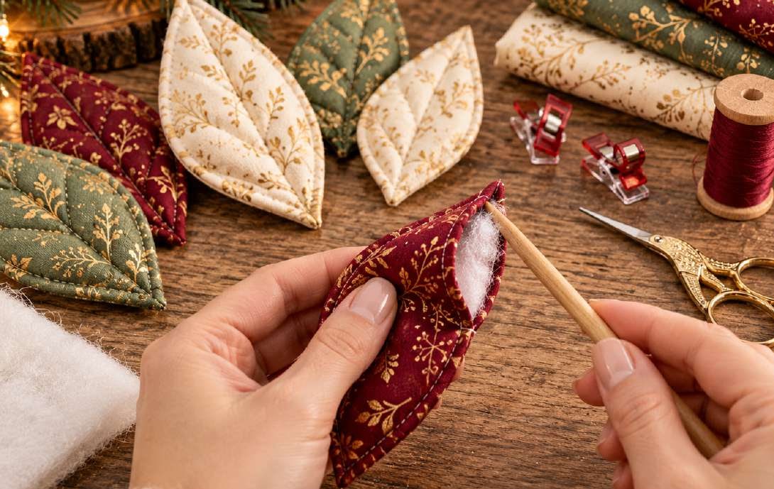 Turning a quilted poinsettia petal right side out through the base opening and shaping the point with a blunt wooden turning tool