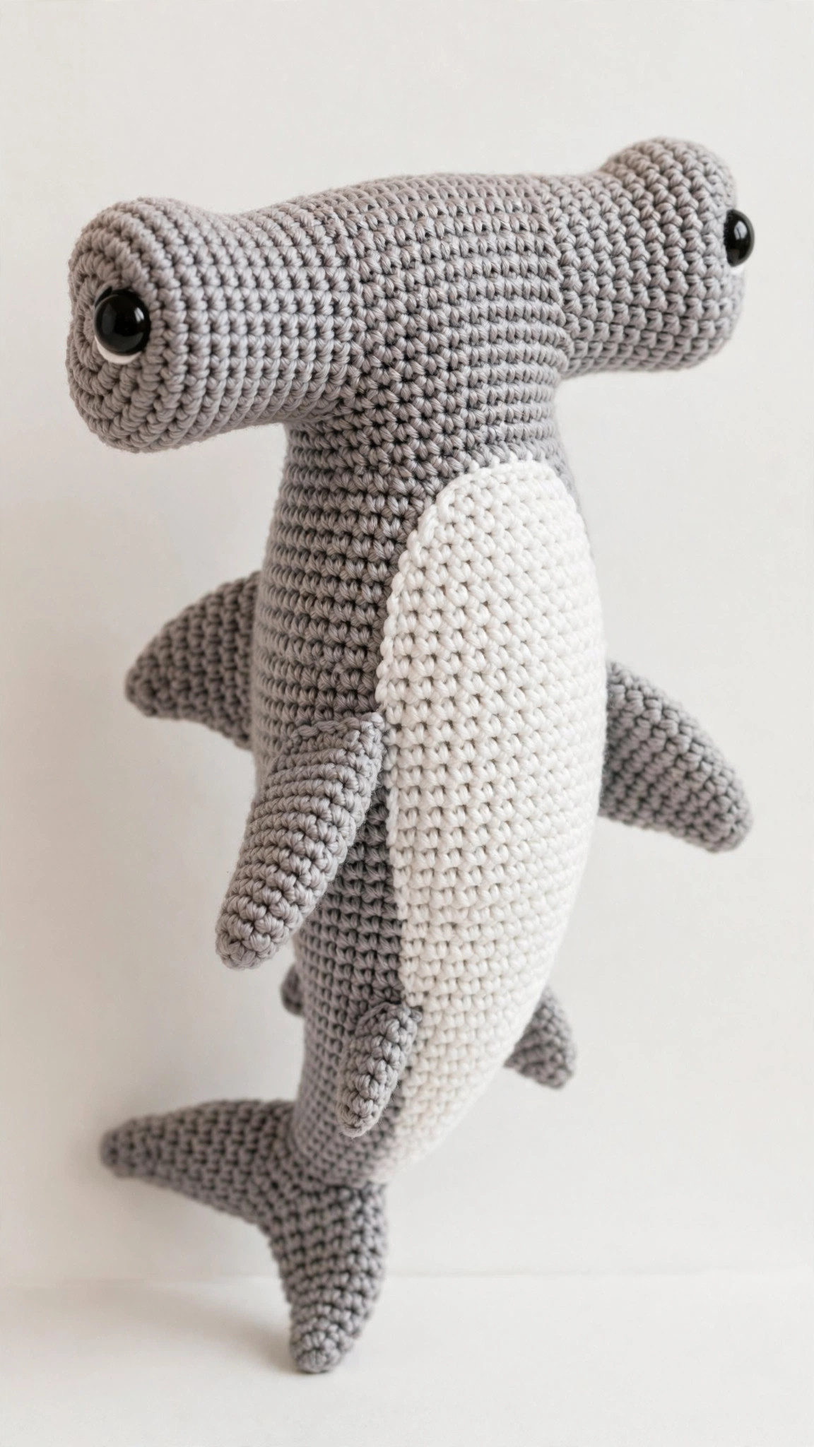 Crochet hammerhead shark pattern — grey amigurumi shark plush with a wide hammer head, safety eyes at each end of the hammer, white belly and tail fin