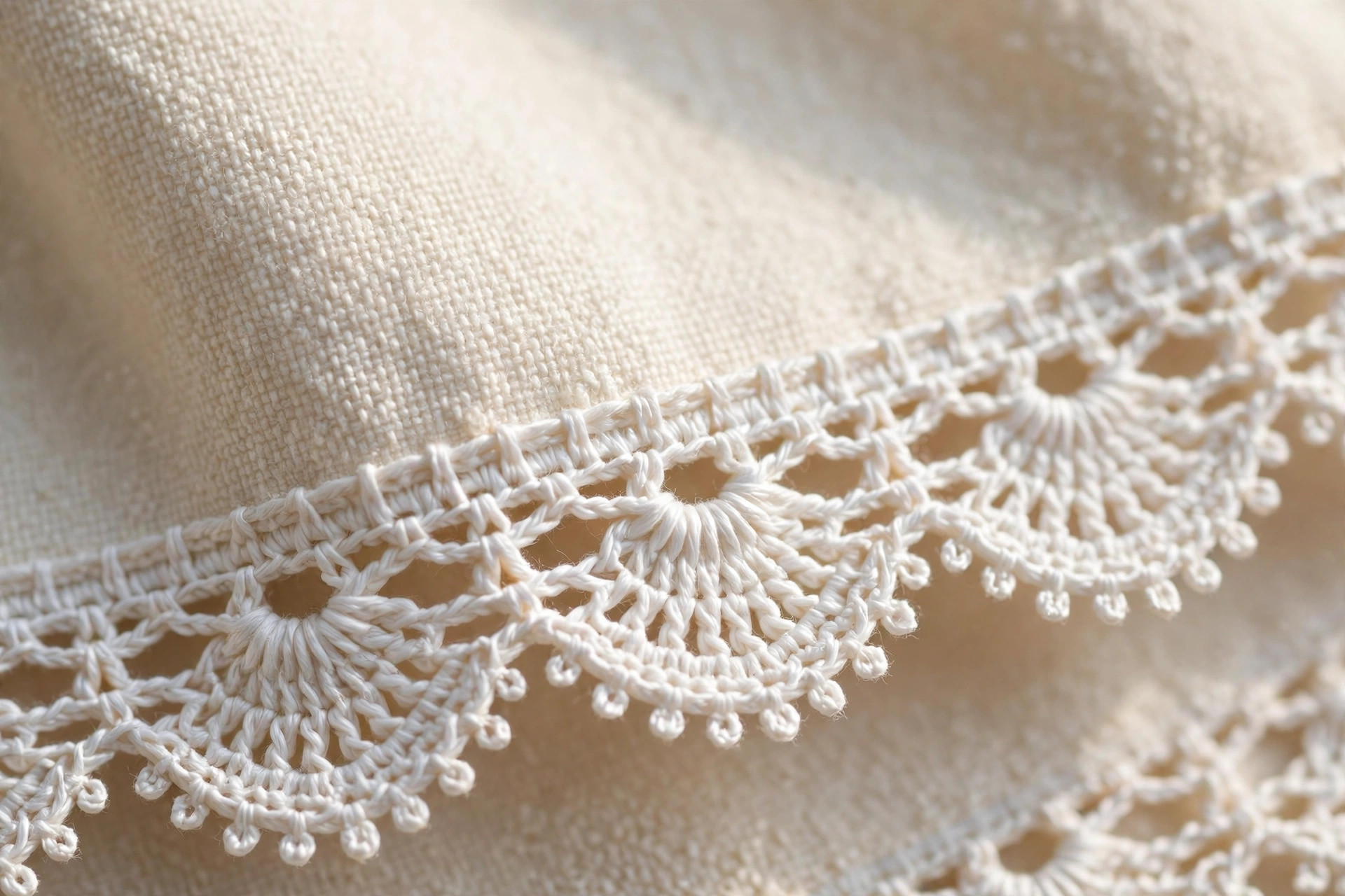 Close-up of white crochet shell lace edging with picots stitched along the hem of a cream cotton towel