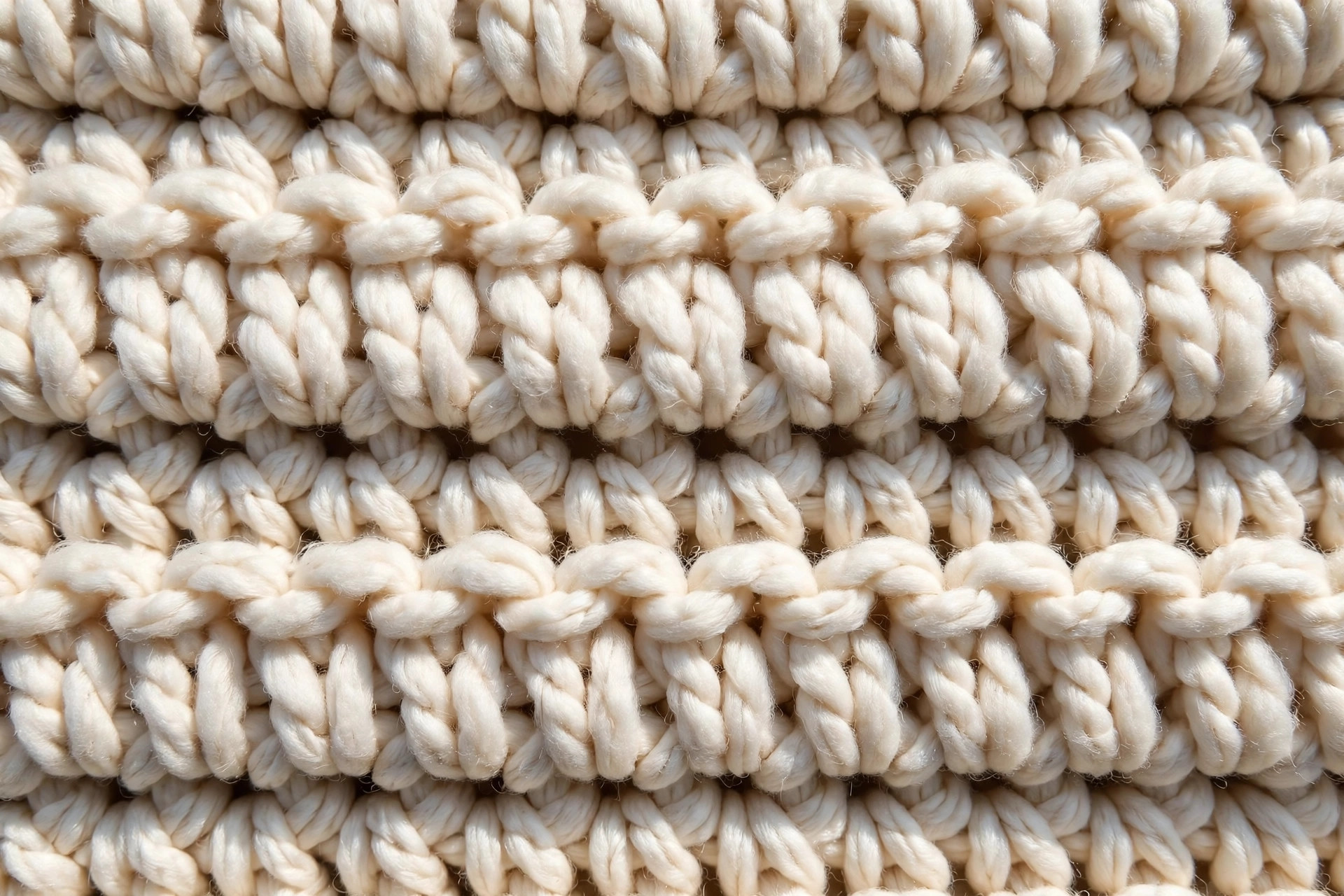 Close-up of half double crochet stitch texture on an oversized sweater panel in soft cream worsted yarn