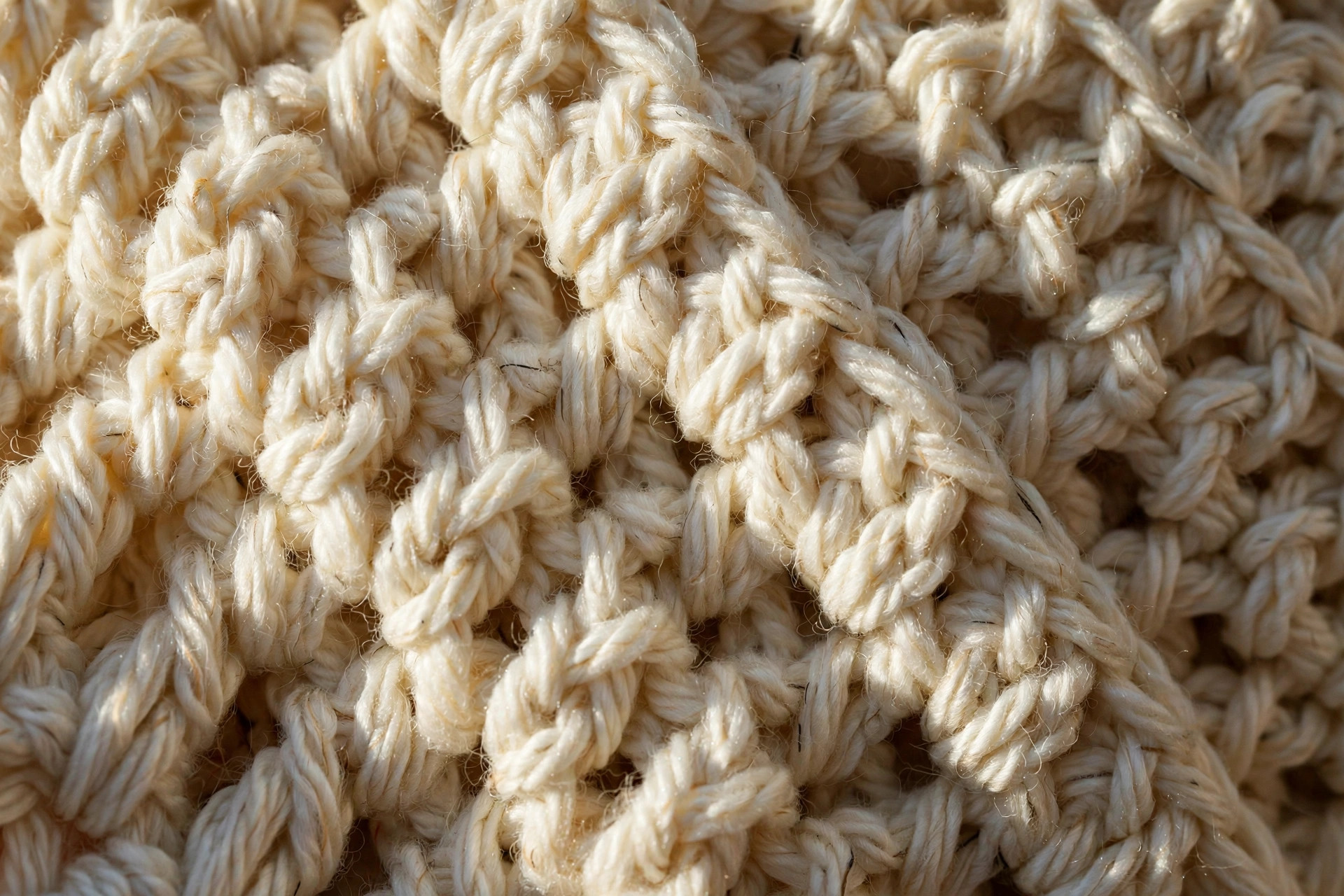 Extreme close-up of the double crochet stitch texture on a handmade cream crochet sweater, simple crochet sweater pattern