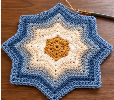 Crochet star with steel blue outer rounds around slate, cream and mustard sections